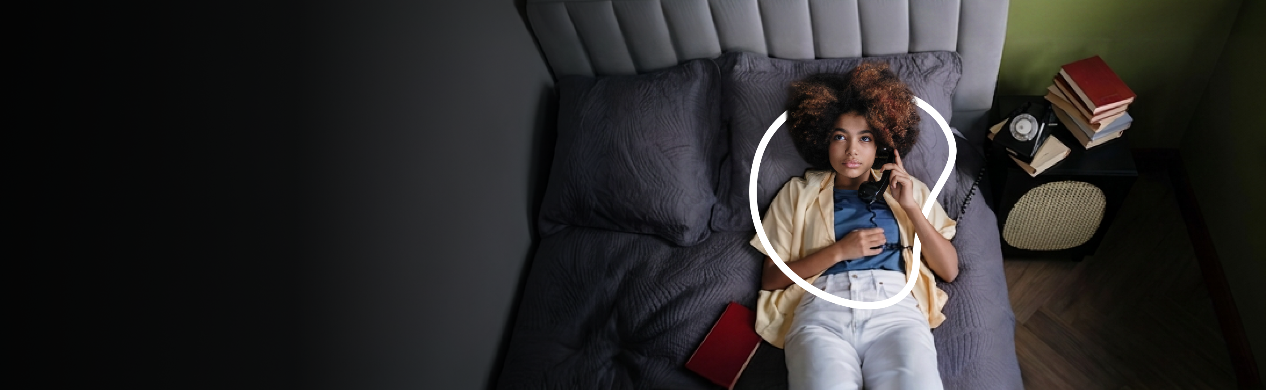 jovem mulher deitada sobre a cama atendendo um telefone fixo
